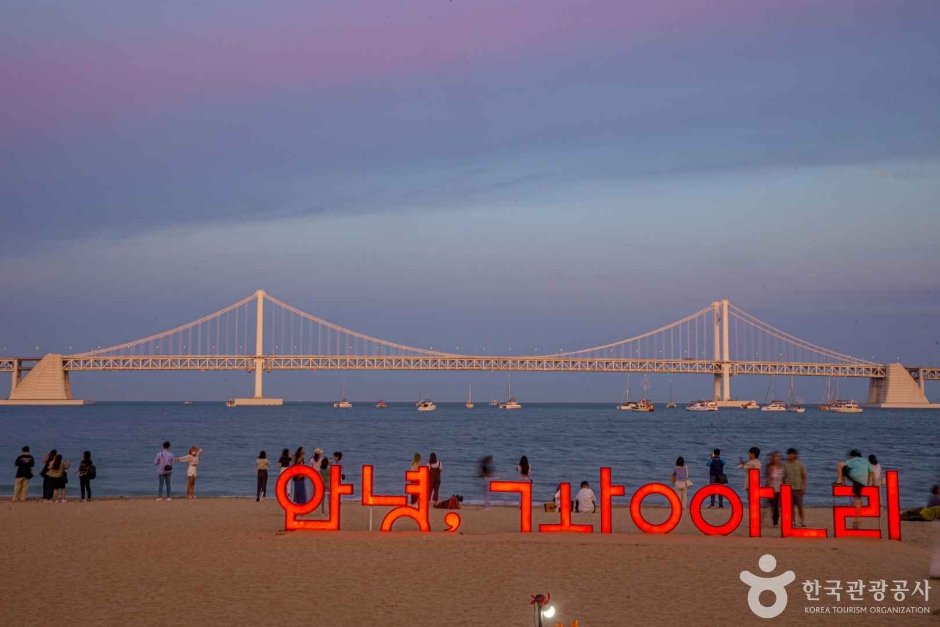 Visitors on Gwangalli Beach at sunset with Gwangan Bridge