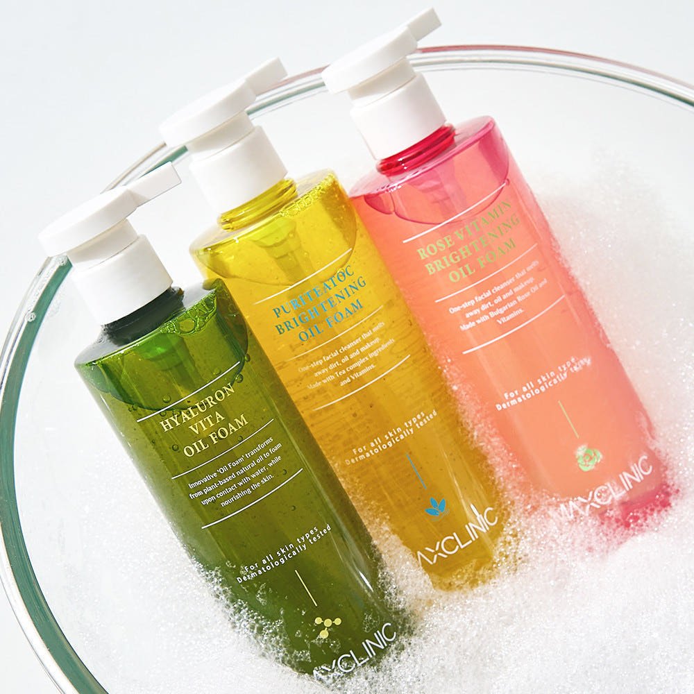 Maxclinic Oil Foam cleansers in green, yellow and pink bottles in a glass bowl of foam