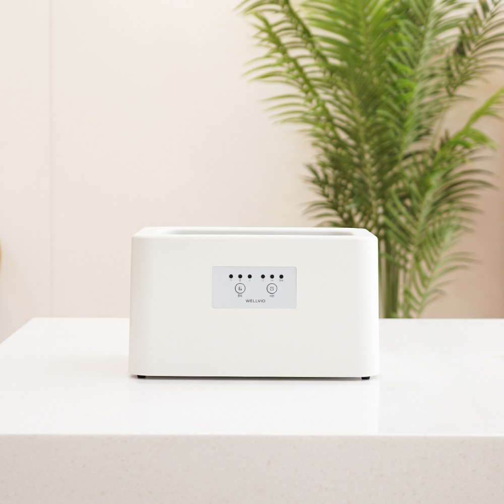 White Wellbio Classic paraffin bath on a counter next to a green plant