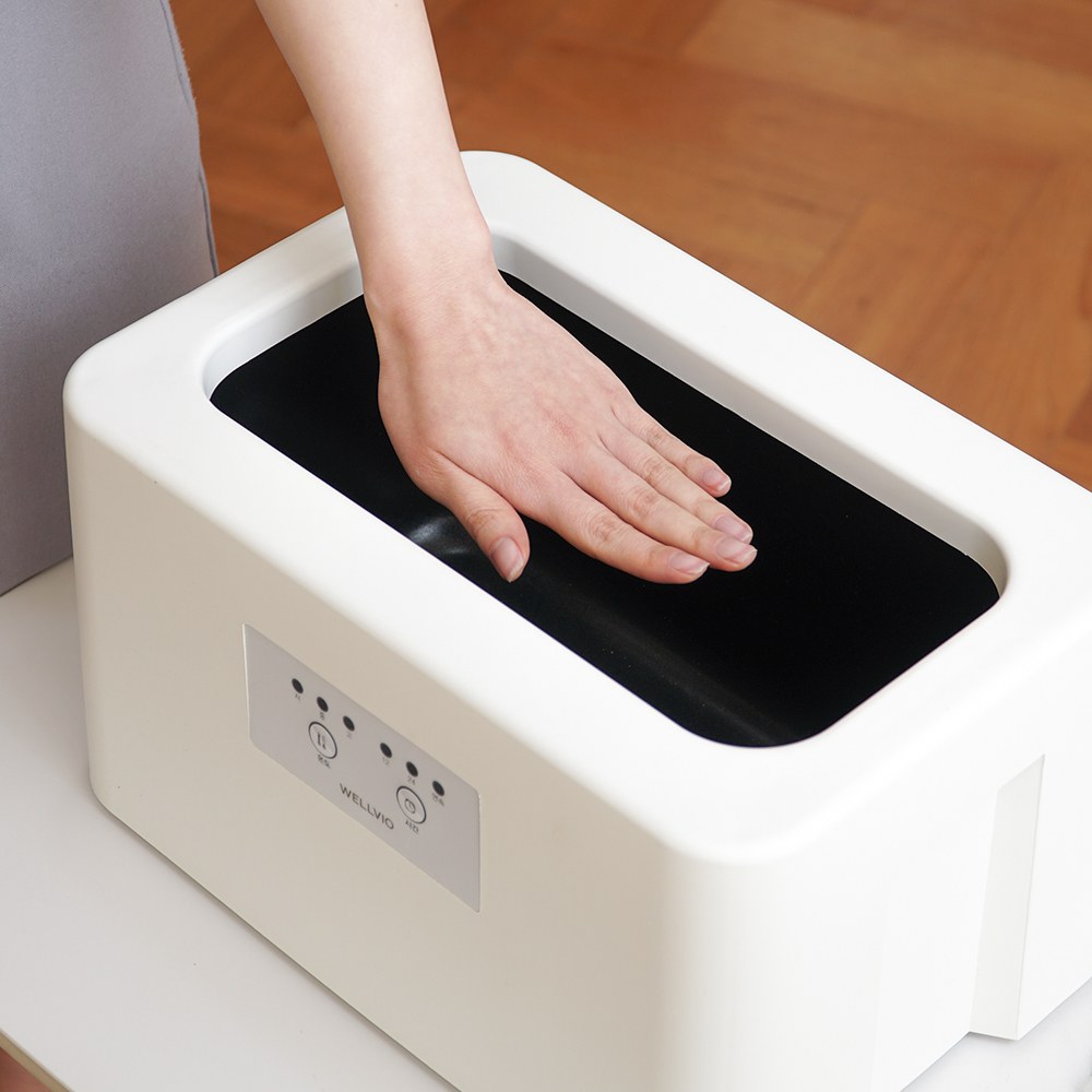 Hand dipping into the open Wellbio paraffin bath tub